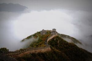 Looking down at an outpost on the Great Wall of China surrounded by mist
